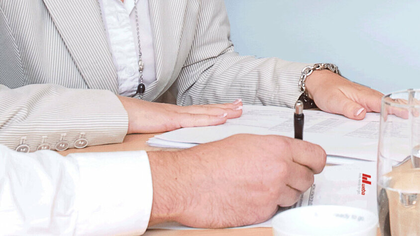 Zwei Personen bei der Durchsicht von Unterlagen und Projektdokumenten im Büro.