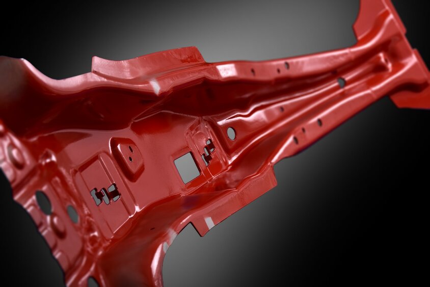 A hot-formed, bright red-colored B-pillar of a car, presented against a deep black background. The B-pillar, known for its structural support between the front and rear doors of a vehicle, is accentuated by the contrast with the dark background. The product was manufactured at weba Werkzeugbau.