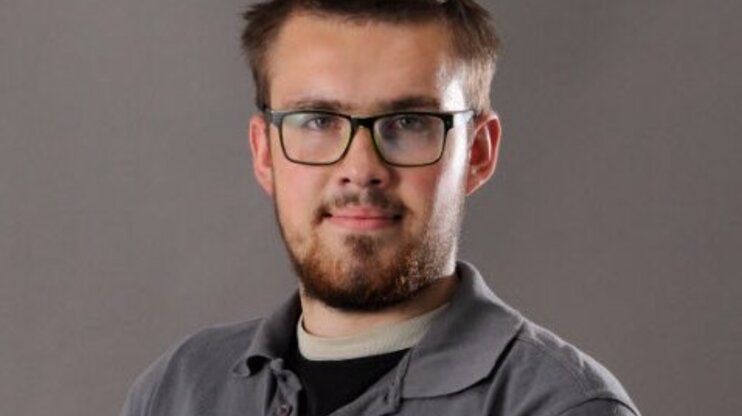 Portrait of toolmaker Jan Wengryn wearing a gray weba polo shirt, smiling confidently in front of a neutral background.