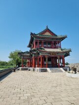 A traditional Chinese pavilion with red wooden façade and ornate roofs by the water – part of Jan Wengryn’s cultural experiences in China.