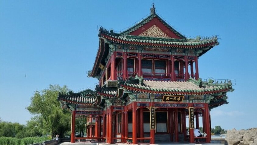 Ein traditioneller chinesischer Pavillon mit roter Holzfassade und reich verzierten Dächern vor blauem Himmel – eine Station aus Jan Wengryns Reise durch China.