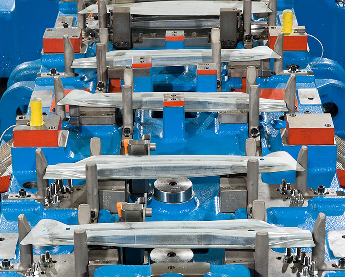 Das Bild zeigt einen Ausschnitt eines Seitenaufprallträger-Transferwerkzeugs, in dem Blechteile in den entsprechenden Fertigungsoperationen positioniert sind.